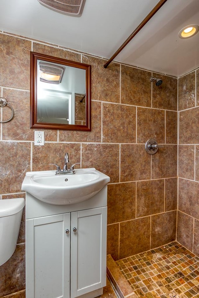 full bath with a tile shower, toilet, vanity, and visible vents