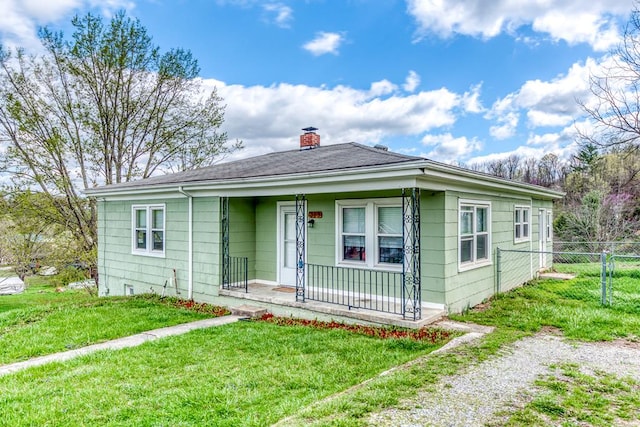 bungalow-style home featuring a porch, a chimney, fence, and a front yard