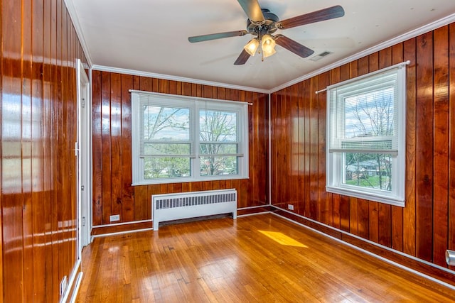 spare room featuring radiator, visible vents, ceiling fan, ornamental molding, and wood-type flooring