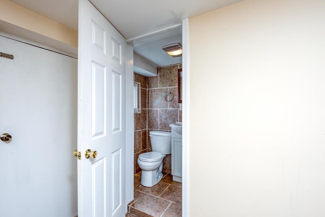 bathroom with tile walls and toilet