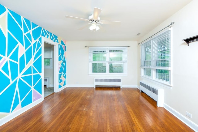 unfurnished room with radiator, baseboards, a ceiling fan, and wood finished floors