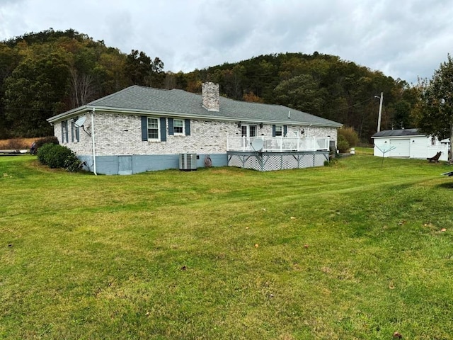 rear view of house featuring a lawn, a chimney, central air condition unit, and a wooden deck