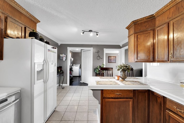 kitchen with crown molding, white refrigerator with ice dispenser, light tile patterned flooring, washer / clothes dryer, and kitchen peninsula