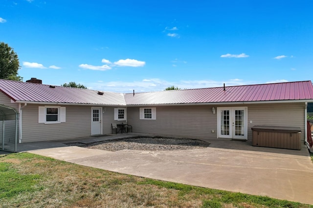 back of property with a hot tub, a patio area, and a lawn