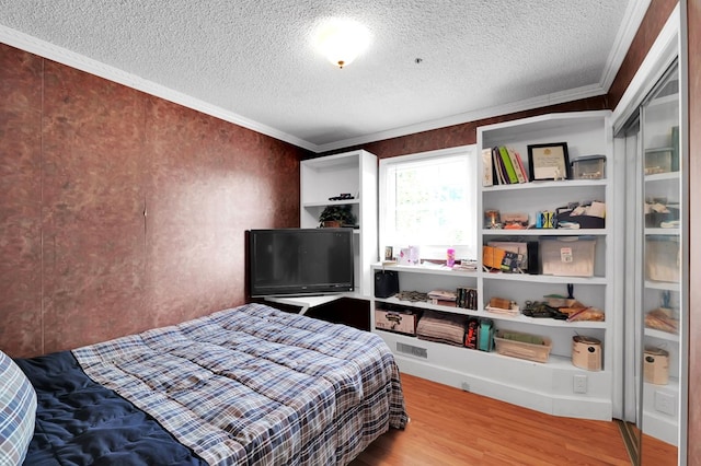 bedroom featuring crown molding, hardwood / wood-style floors, and a textured ceiling