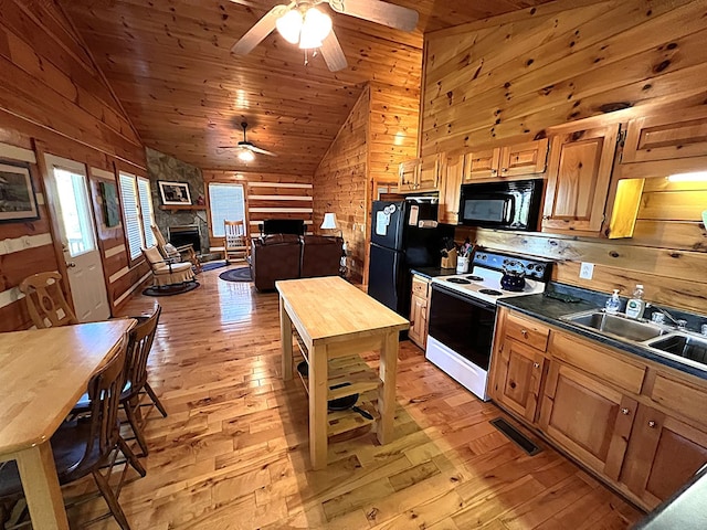 805 Double Bridges Dr, Fancy Gap, VA 24328 - kitchen featuring black appliances, a fireplace, a ceiling fan, wooden walls, and light wood-style floors