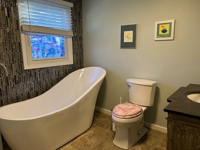 bathroom featuring a tub to relax in, toilet, and vanity