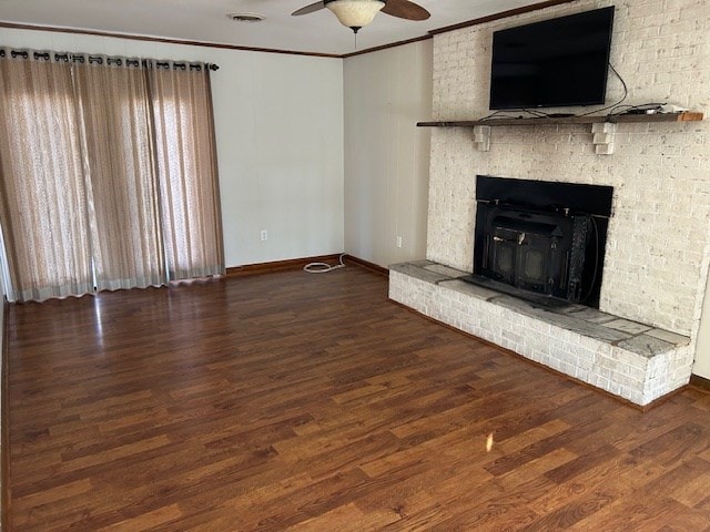 unfurnished living room with a fireplace, dark wood-type flooring, ornamental molding, and ceiling fan