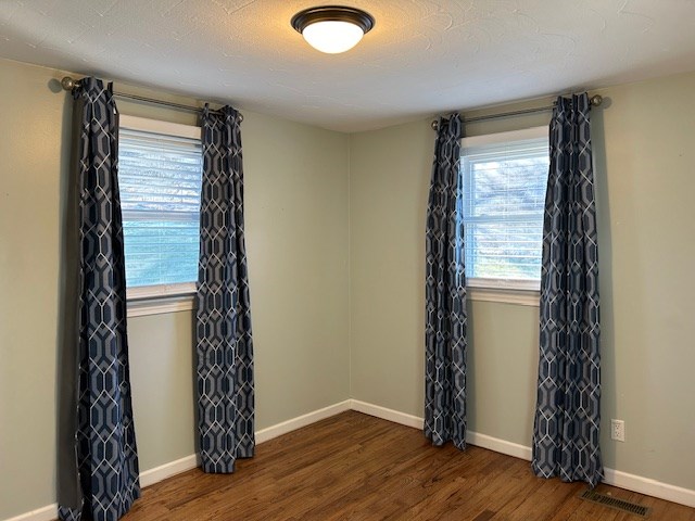 empty room featuring dark hardwood / wood-style floors and a textured ceiling