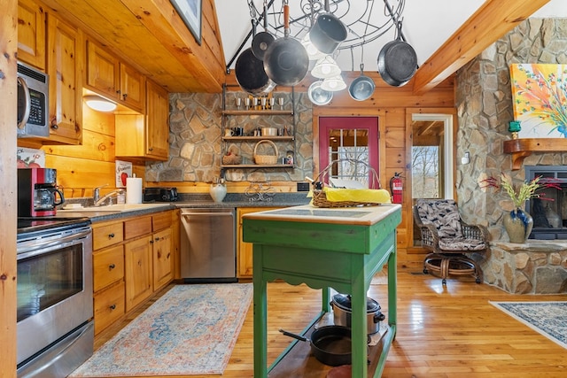 799 Crystal Springs Dr, Fancy Gap, VA 24328 - kitchen featuring stainless steel appliances, light wood-style floors, beam ceiling, a fireplace, and brown cabinetry