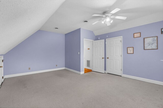 bonus room with visible vents, a textured ceiling, baseboards, and vaulted ceiling