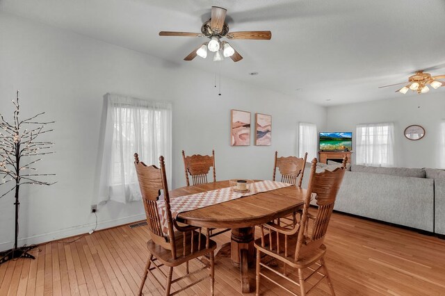 dining room with a ceiling fan, light wood-style flooring, a fireplace, and visible vents