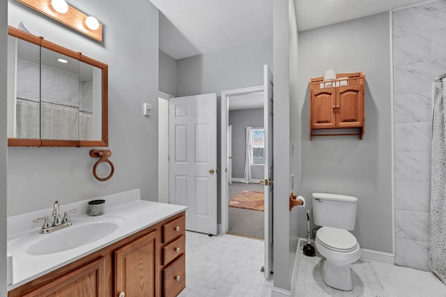 bathroom with toilet, vanity, and baseboards