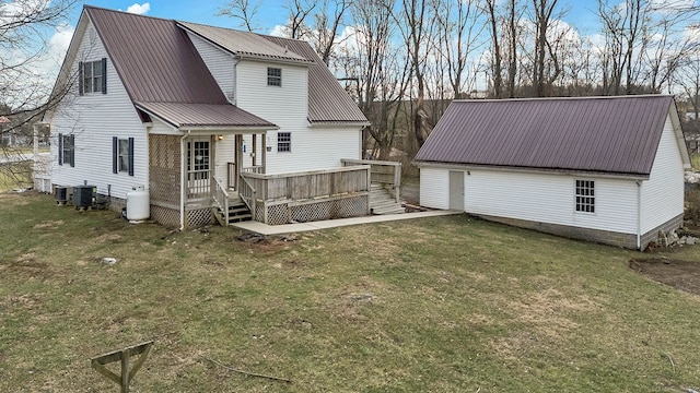 back of property featuring central AC unit, a wooden deck, an outdoor structure, a lawn, and metal roof