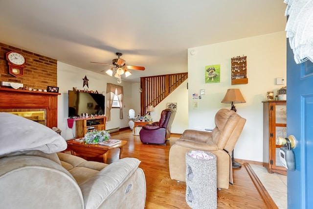 living room featuring baseboards, stairway, a ceiling fan, and light wood finished floors