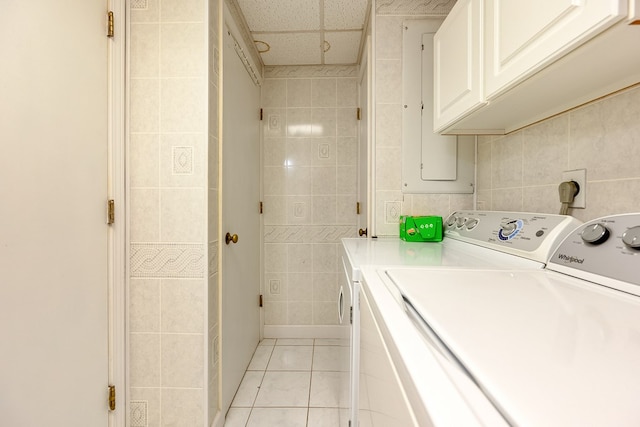 laundry room with washing machine and dryer, cabinet space, tile walls, and light tile patterned floors