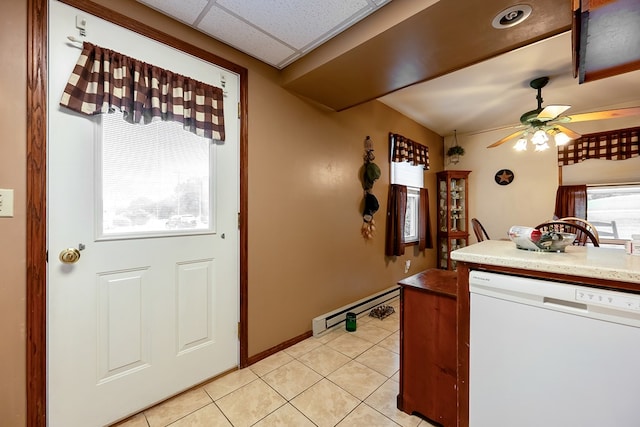 kitchen featuring a ceiling fan, baseboard heating, white dishwasher, light tile patterned floors, and a paneled ceiling