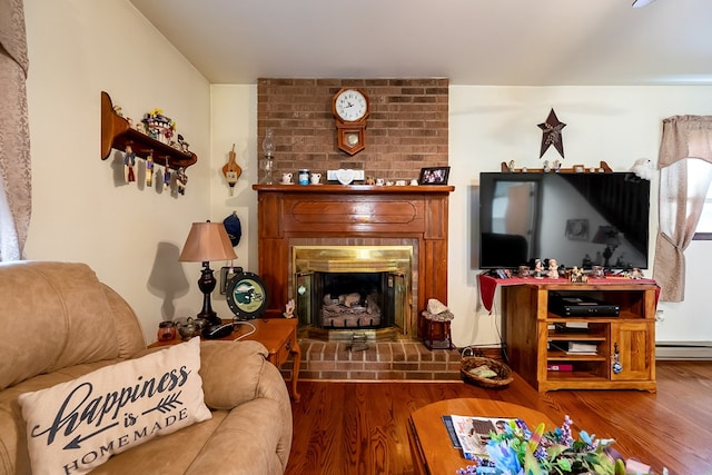 living room with a baseboard heating unit, a fireplace, and wood finished floors