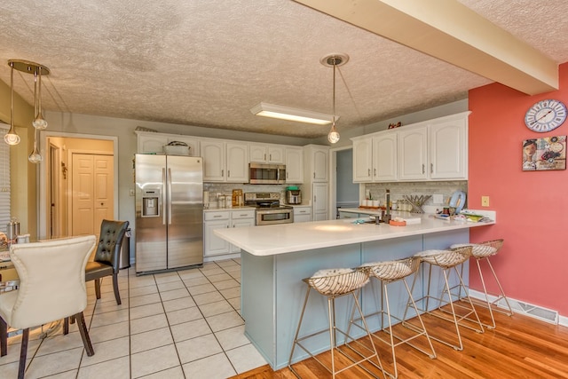 17031 Sedona Dr, Abingdon, VA 24211 - kitchen featuring appliances with stainless steel finishes, decorative backsplash, a peninsula, a textured ceiling, and a kitchen bar