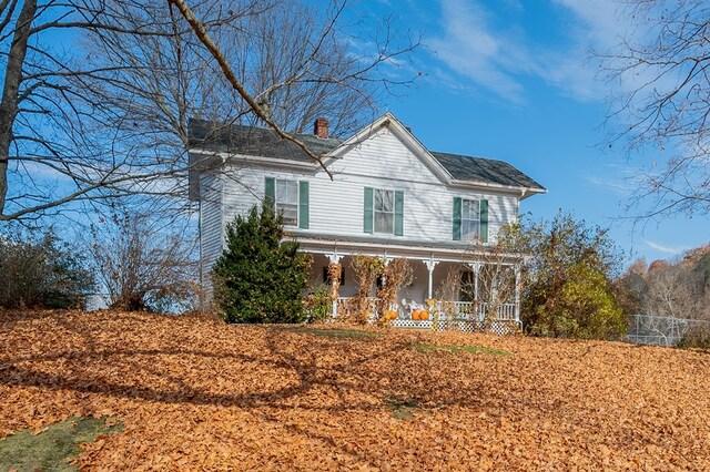 view of front of home with a chimney and a porch