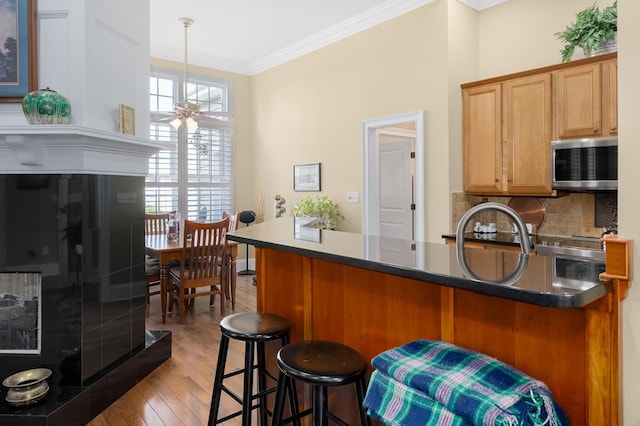 20324 Josh Allen Dr, Abingdon, VA 24211 - kitchen with light wood finished floors, crown molding, a ceiling fan, a breakfast bar area, and stainless steel microwave