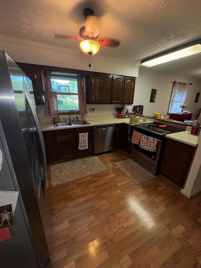 kitchen with a textured ceiling, a sink, dark brown cabinets, and stainless steel appliances