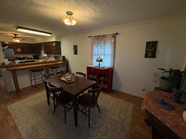 dining space with light wood finished floors, a textured ceiling, ceiling fan, and baseboards