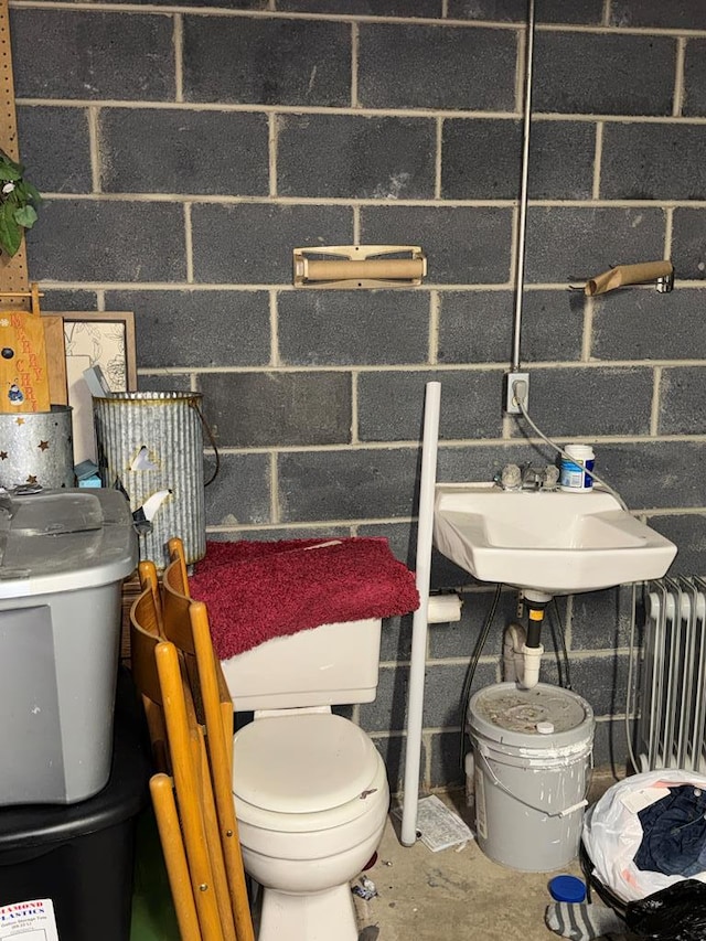 half bathroom featuring radiator heating unit, toilet, and a sink