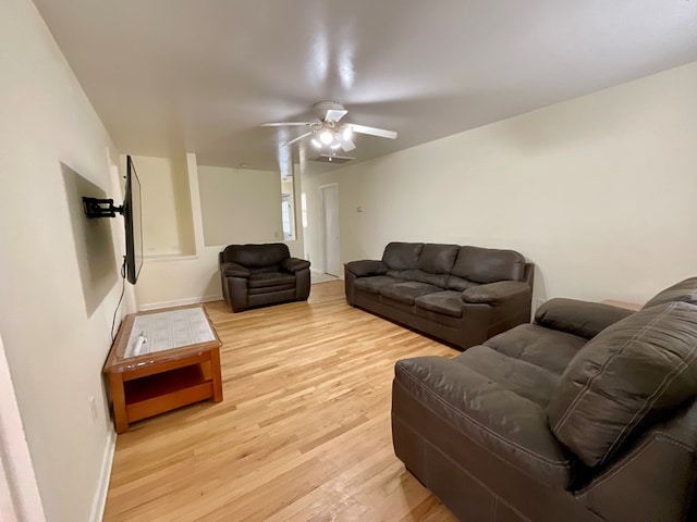 living room featuring baseboards, light wood-style floors, and a ceiling fan