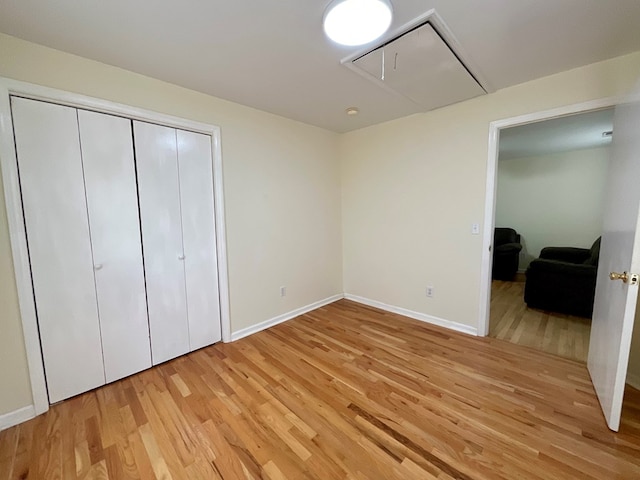 bedroom featuring baseboards, light wood-style flooring, a closet, and attic access