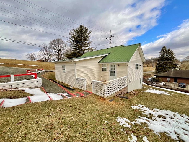 back of property with metal roof, fence, and a yard