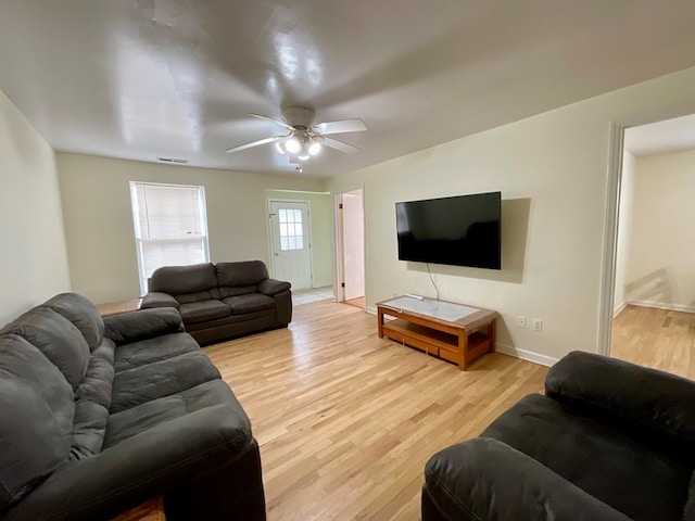living room featuring baseboards, visible vents, light wood-style flooring, and ceiling fan