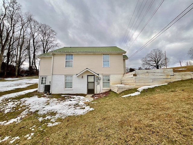 snow covered property featuring a lawn and metal roof