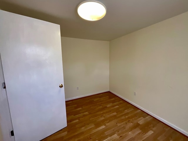 unfurnished room with baseboards and wood finished floors