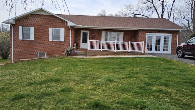single story home featuring brick siding, a front lawn, french doors, and covered porch
