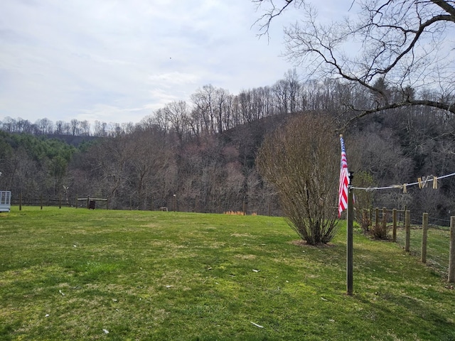 surrounding community with a lawn, fence, and a view of trees