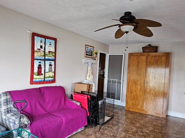 living room featuring baseboards, a textured ceiling, and a ceiling fan