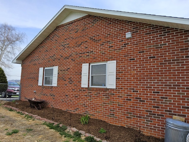 view of property exterior featuring brick siding and fence