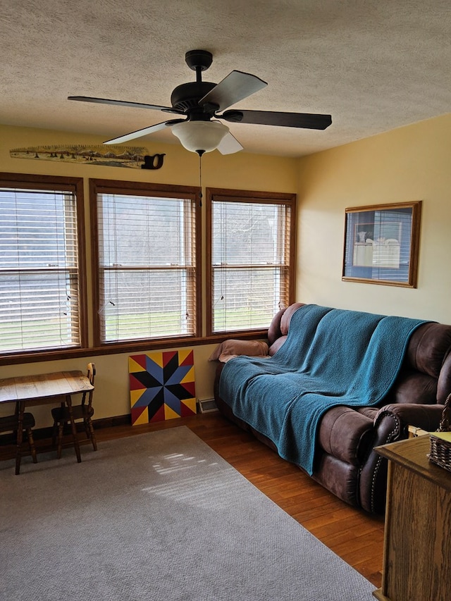living room with a textured ceiling, visible vents, a ceiling fan, and wood finished floors