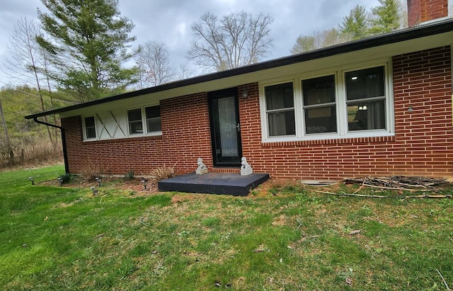 exterior space with brick siding and a yard