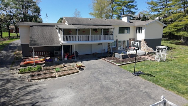 rear view of property with a patio area, an attached garage, a vegetable garden, a lawn, and aphalt driveway