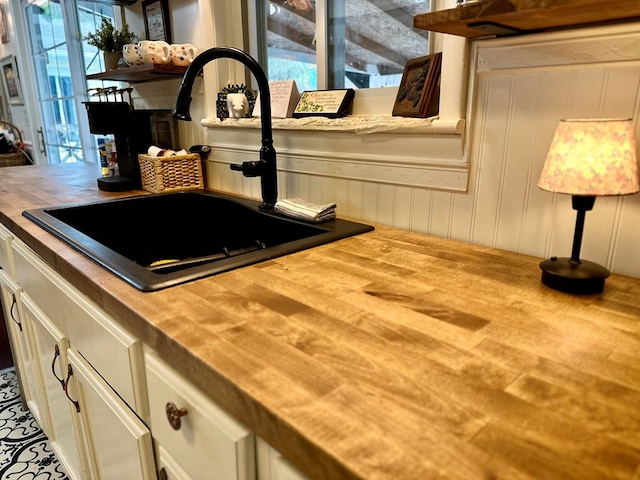 details with wood counters, open shelves, a sink, and white cabinets