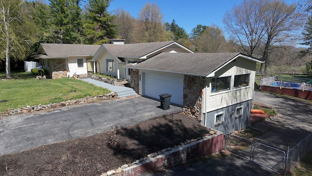 single story home featuring a front lawn, stone siding, an attached garage, fence, and roof with shingles