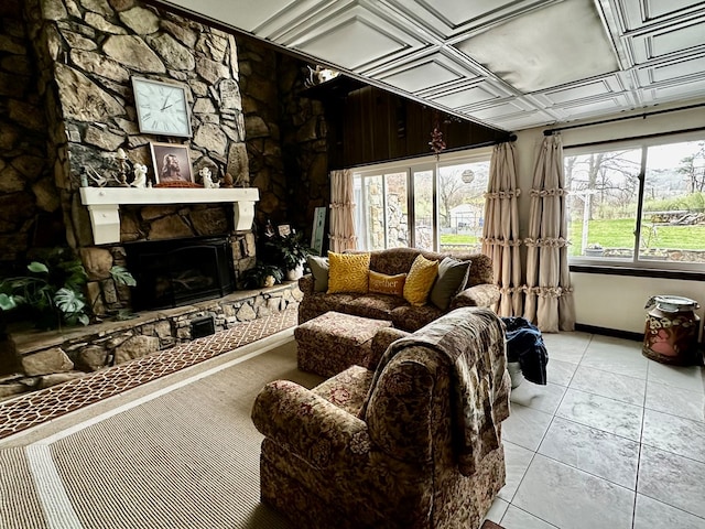 tiled living area with baseboards and a stone fireplace