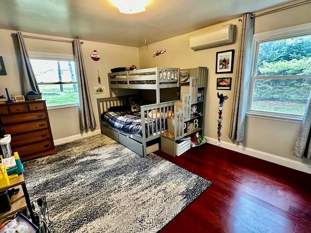 bedroom featuring wood-type flooring, baseboards, multiple windows, and a wall unit AC