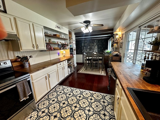 kitchen featuring stainless steel electric stove, open shelves, wooden counters, and under cabinet range hood
