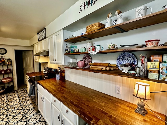 kitchen featuring open shelves, under cabinet range hood, range with electric cooktop, and butcher block countertops