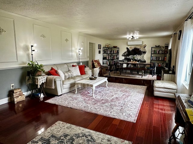 living area with a wall mounted air conditioner, a textured ceiling, and wood finished floors
