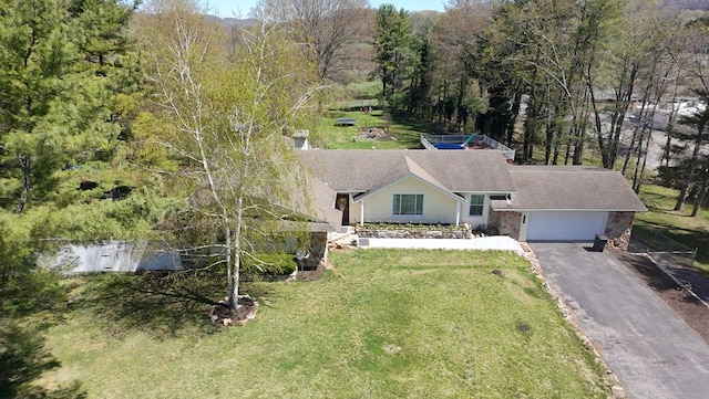 view of front of house with stone siding, aphalt driveway, a front yard, and a garage