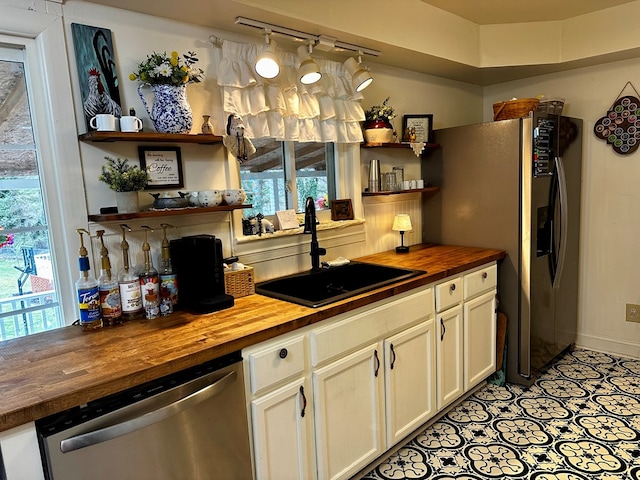 kitchen featuring wooden counters, open shelves, rail lighting, a sink, and appliances with stainless steel finishes